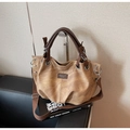 Detail of vintage brown tote bag showing textured canvas and leather strap on metal stand - Khaki