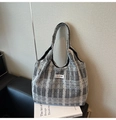 Detail of grey checkered canvas tote bag with black dots on a modern leather sofa - Black