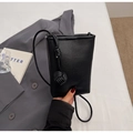 Detail showing the pebble grain leather texture and signature knot of the black phone bag - Black