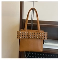Nahaufnahme der karamellfarbenen Ledertasche mit Metallnieten und großer Schleife - Braun