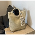 Beige woven straw tote bag with evil eye bead tassel on a rustic stone background - Off-white