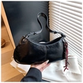 Detail of black oiled leather crescent bag with adjustable handle and woven charm accessory - Black with Pendant