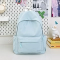 Close-up of light blue nylon travel backpack with GDMN embroidery on a decorative background - Blue