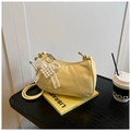 Détail d'un sac froncé jaune clair avec breloque cœur perlé sur un fond de style épuré - Jaune