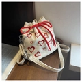 Detail shot of corduroy bucket bag featuring red heart embroidery and drawstring closure - Off White