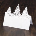 Macro shot of white laser-cut Christmas tree table cards on a dark wood background - 10*10CM / White