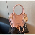 Gros plan du sac seau rose avec texture plissée et charmant pendentif ours en peluche - Rose avec pendentif