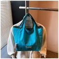 Détail d'un sac cabas en nylon bleu avec bordure verte et étiquettes de marque - Bleu