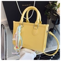 Détail du sac cabas en cuir jaune avec charms colorés sur une surface métallique - Jaune (Avec Pendentif)