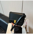 Détail d'un sac bandoulière noir avec boucle dorée et nœud en dentelle blanche élégant - Noir avec pendentif