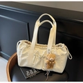 Détail du sac cabas crème à cordon avec breloque ours en peluche sur siège en cuir - Avec Pendentif / Blanc Cassé