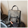 Détail d'un sac à dos vintage en toile grise avec lanières en cuir et texte embossé - Noir