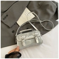 Detail shot of mini silver barrel bag with twin buckle straps on grey blazer fabric - Silver