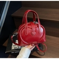 Détail du sac Boston rouge brillant avec motif cœur embossé et petit ornement cœur - Bordeaux