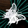 Close-up of white laser-cut butterfly napkin ring on green satin and wood background - White