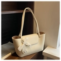 Détail d'un sac cabas beige avec nœud en dentelle et pendentif en perles sur étagère - Blanc Cassé