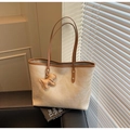 Dettaglio di una borsa tote crema goffrata coccodrillo con manico marrone e ciondolo a cane - Con Ciondolo / Cachi