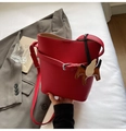 Detail of red lychee leather bucket bag featuring a designer horse charm and silver buckle - Red with Pendant