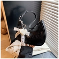 Détail d'un sac hobo en cuir verni noir avec nœud en dentelle et pendentif en perles - Noir avec pendentif