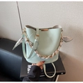 Détail du sac seau en cuir vert menthe avec poignée en chaîne dorée et foulard en soie - Vert