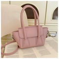 Detalle del bolso rosa de cuero sintético con grano lichi sobre un libro abierto - Rosa