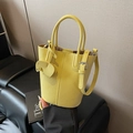 Yellow litchi leather bucket bag with elephant pendant and adjustable shoulder strap - Yellow