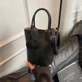 Black litchi grain bucket bag with dual handles and a decorative elephant charm - Black