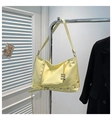 Close-up of a glossy yellow punk tote bag with studs and grommets on a metal hanger - Yellow