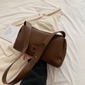 Dark brown pleated pillow bag with adjustable strap and golden studs in a lifestyle setting - Brown