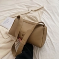 Khaki pleated cylinder shoulder bag with adjustable strap held by a model - Khaki