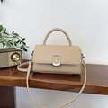 Beige woven texture crossbody bag with silver buckle and top handle on a wooden desk - Khaki