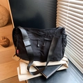 Black nylon crossbody messenger bag with a red logo tag and adjustable wide shoulder strap - Black