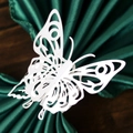 Detail of laser-cut white paper butterfly napkin ring on a green satin cloth - White