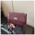 Detail of burgundy crocodile-textured bag featuring silver chain and square twist lock - Burgundy