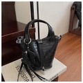 Close-up of black crocodile pattern bucket bag with silver lock and bear charm accessory - Black