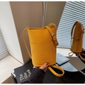 Detail of yellow textured cross-body bucket bag with silver hardware and adjustable strap - Pebble Grain Bucket Crossbody Style / Yellow