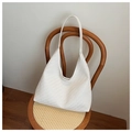 Detail der weißen Flechtstruktur einer Vintage-Hobo-Tasche, die an einem Stuhl hängt - Weiß