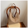 Detail einer geflochtenen Hobo-Tasche in Tan an einem Vintage-Holzstuhl vor weißer Wand - Khaki
