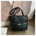 Detailed view of black quilted tote bag with diamond pattern and metal logo plate - Black