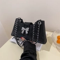 Black suede baguette bag featuring a silver metal bow buckle and chain shoulder strap - Black