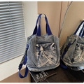 Détail du sac en jean délavé montrant la poche style utilitaire et les sangles bicolores - Bleu foncé
