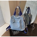Détail d'un sac à dos en jean bleu clair avec poches multiples et sangles en nylon - Bleu