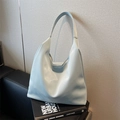 Bolso tote grande de cuero azul claro minimalista sobre un sofá negro moderno - Azul