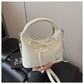 Close-up of cream leather handbag featuring a 3D bow and silver metal chain strap - Off White