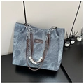 Dettaglio borsa tote in denim con manici in pelle marrone, perle e catena d'argento - Blu