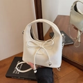 Minibolso chic blanco roto con lazo y cadena plateada mostrado sobre escritorio - Blanco Roto