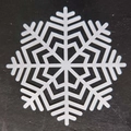 Top view of laser-cut white snowflake coaster with geometric pattern on black surface - Snowflake Style F(F)