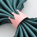 Close-up of pink crown paper napkin ring on dark green fabric for party decoration - Pink