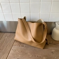 Borsa tote minimalista in pelle cammello con trama litchi su un supporto di legno - Albicocca
