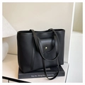 Detalle de bolso tote negro de cuero granulado con bolsillo de solapa ondulada y botón de oro - Negro